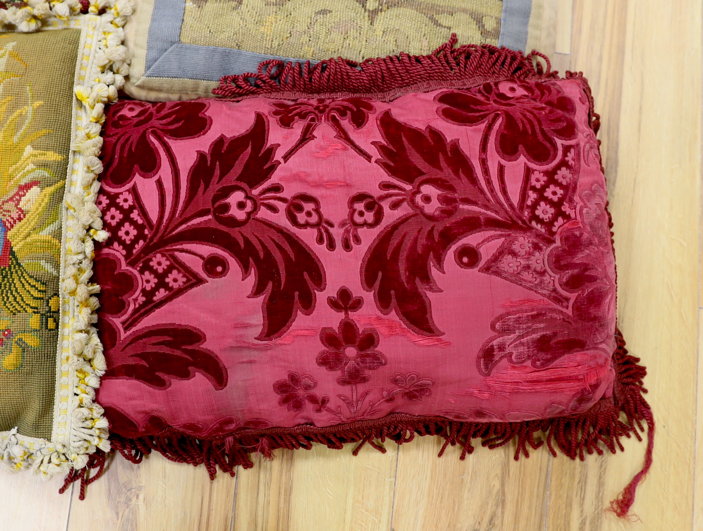 A late 18th century Flemish verdure tapestry fragment made into a cushion, a similar burgundy silk velvet damask cushion and two 19th early 20th century wool worked cushions (4)